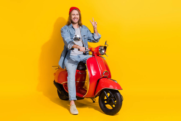 Full length photo of funky cool man wear denim jacket riding moped showing v-sign isolated yellow color background. - Fotoğraf, Görsel