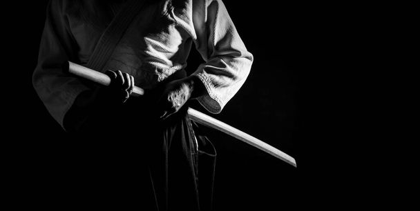 Uma pessoa em hakama preto em pé na luta pose com bokken espada de madeira em preto e branco. Profundidade de campo rasa. FDS.  - Foto, Imagem