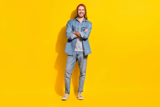 Photo of handsome friendly nice guy with long hairstyle dressed jeans shirt standing arms folded isolated on yellow color background. - Zdjęcie, obraz