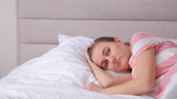 Droevige vrouw ligt in bed, ze lijdt aan slapeloosheid. Hoge kwaliteit 4k video. - Video