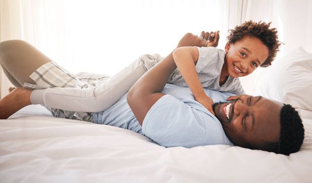 Kinderen, liefde en slaapkamer met een speelse zwarte familie die 's morgens samen plezier hebben na het wakker worden. Kinderen, lachen of lachen met een vader en een gelukkige zoon die spelen of grapjes maken in hun huis. - Foto, afbeelding
