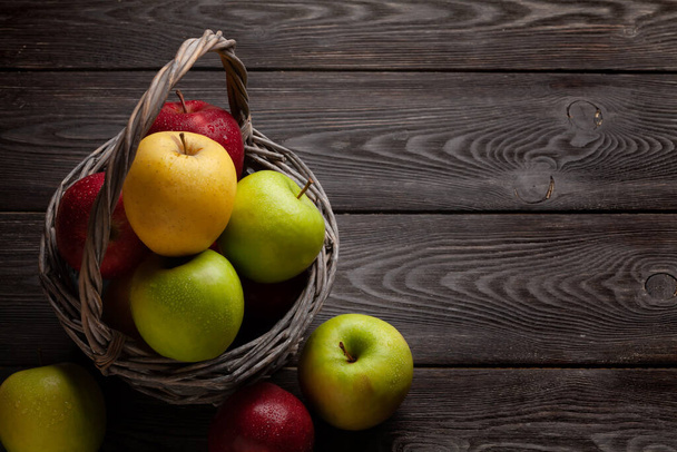 Barevné zralé jablečné ovoce v košíku na dřevěném stole. S mezerou pro kopírování - Fotografie, Obrázek
