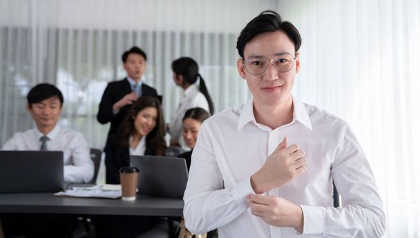 Portrait of focus young successful confident male manager, executive wearing business wear in harmony office arm crossed with blurred meeting background of colleagues, office worker. - Foto, immagini
