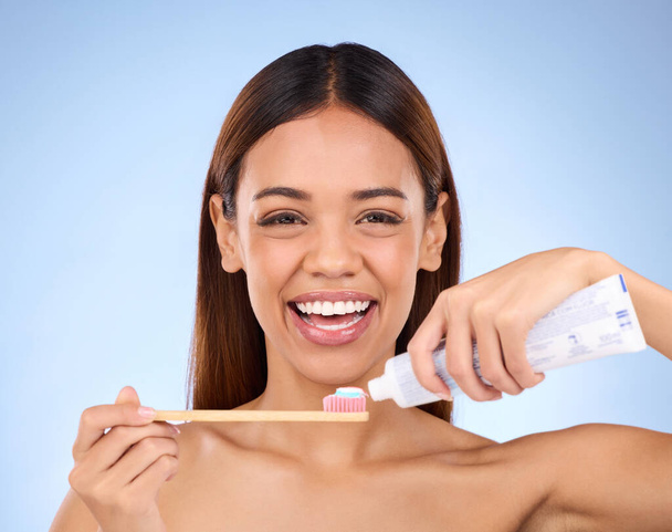 Portrait, toothbrush and dental with a model woman in studio on a blue background for oral hygiene. Mouth, cleaning and smile with an attractive young female brushing her teeth for whitening. - Photo, image