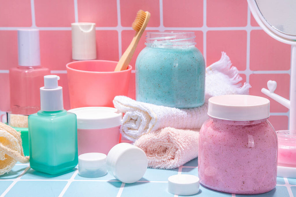 Bath background with cosmetics, cream, scrub, toothbrush, serum, mirror pink and blue tiled bright background. Cute bright self care, spa, relax, time for yourself concept. - 写真・画像