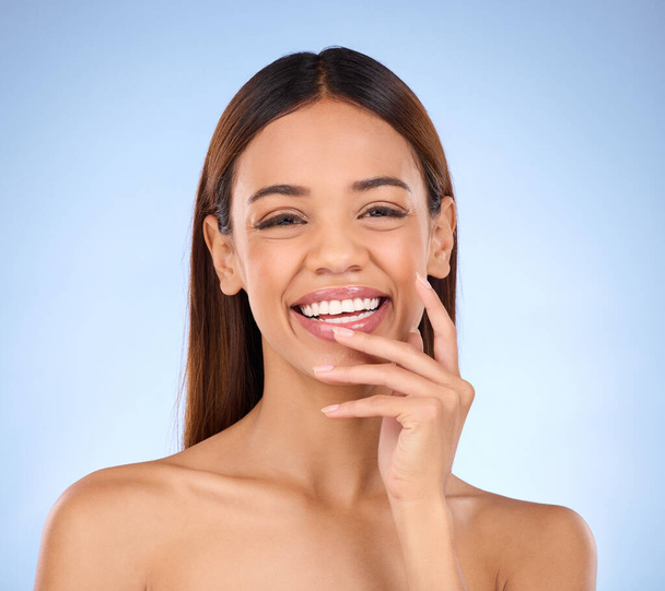 Portrait, skincare and woman with laugh, cosmetics and happiness against blue studio background. Face, Latino female and lady with smile, dermatology and morning routine for confidence and soft skin. - 写真・画像