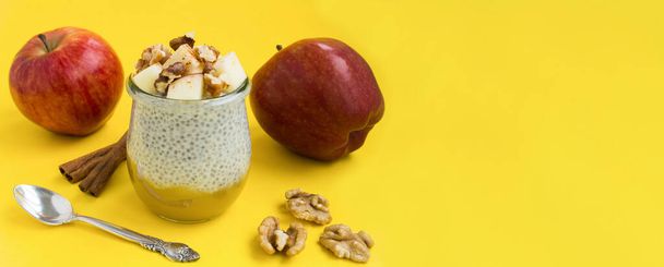 Pudding mit Chiasamen, Apfel, Zimt und Walnüssen auf gelbem Hintergrund. Kopierraum. Nahaufnahme. - Foto, Bild