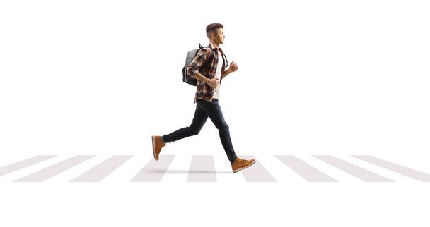Volledige profielfoto van een mannelijke student die over een voetgangersoversteekplaats loopt, geïsoleerd op witte achtergrond - Foto, afbeelding