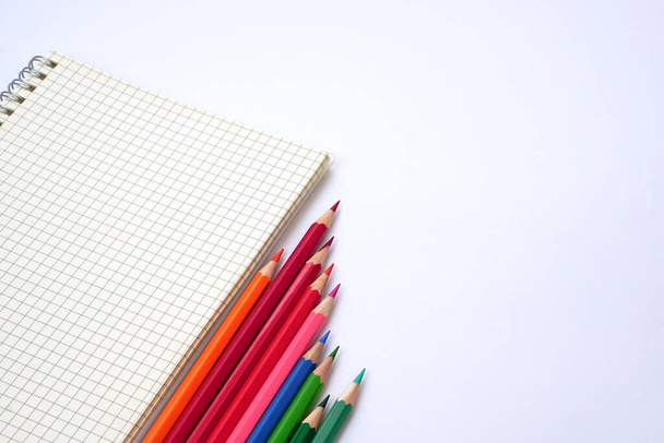 Grafická kniha s barevnými tužkami nebo pastelem seřazená na bílém pozadí. Koncepce učení, studia a prezentace. - Fotografie, Obrázek