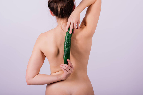 Close up portrait of an attractive young woman topless with cucumber in studio - Photo, Image