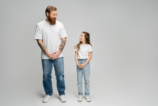 Full length of positive father and daughter looking at each other on grey background - Fotoğraf, Görsel