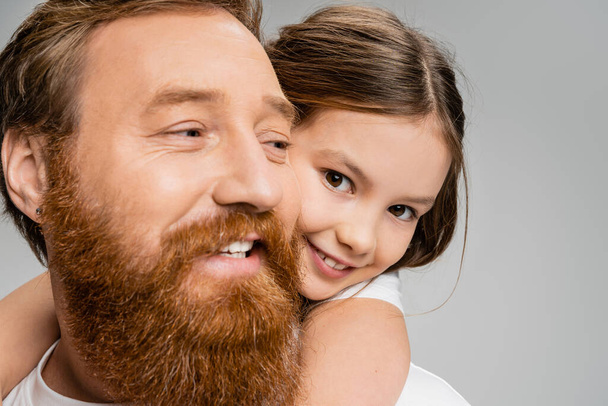 Портрет счастливой девушки, обнимающей бородатого папу, изолированного на серой  - Фото, изображение