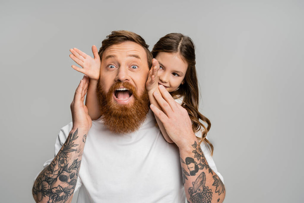 Smiling girl touching face of excited father isolated on grey  - Photo, Image