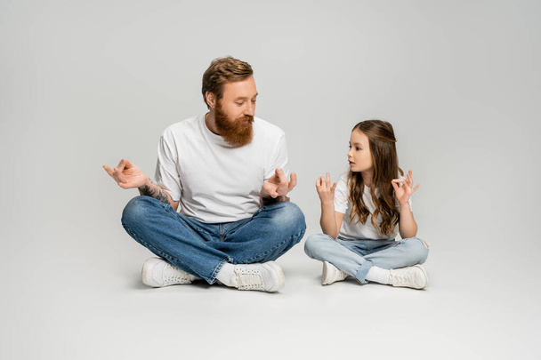 Kid and bearded dad doing gyan mudra while sitting on grey background - Fotoğraf, Görsel