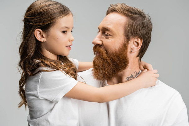 Preteen girl hugging and talking to bearded dad isolated on grey   - Фото, зображення