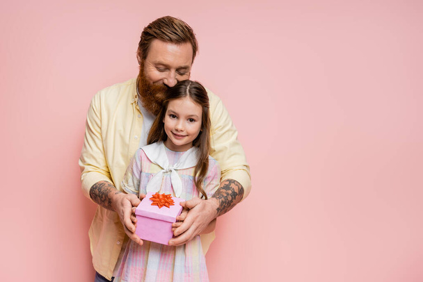 Overjoyed man holding present near preteen child on pink background  - Valokuva, kuva