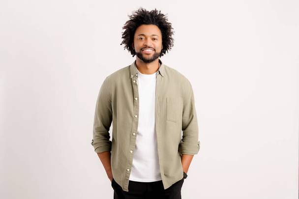 Proud and pleased african-american man in casual wear standing isolated on white. Male standing in confident pose and looking at camera - Foto, afbeelding