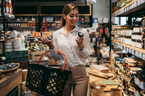 Beautiful young and elegant woman buying some healthy food and drink in modern supermarket or grocery store. Lifestyle and consumerism concept. - Photo, Image