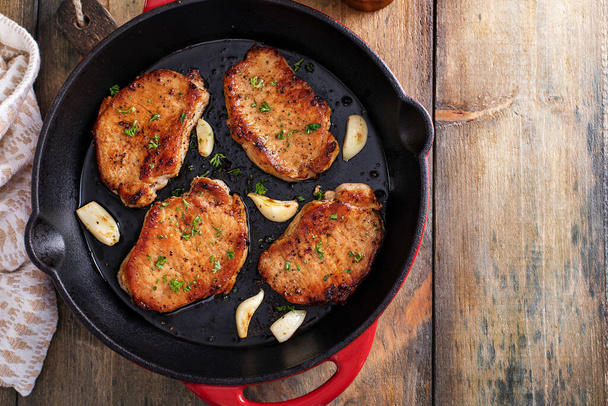 Pork chops cooked with garlic in a cast iron pan - Фото, изображение