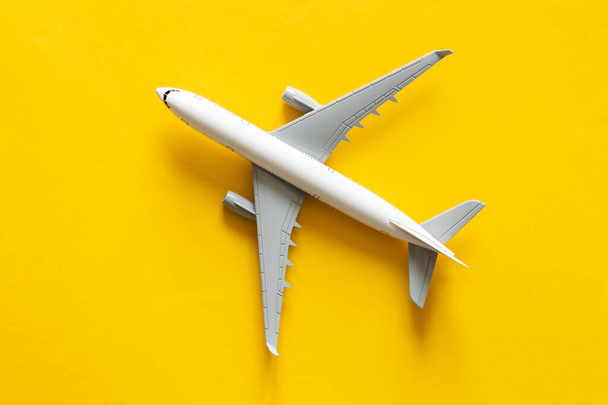 Sarı zemin üzerinde uçak modeli izole, düz konum, uçak bileti, seyahat ve tatil konsepti. - Fotoğraf, Görsel