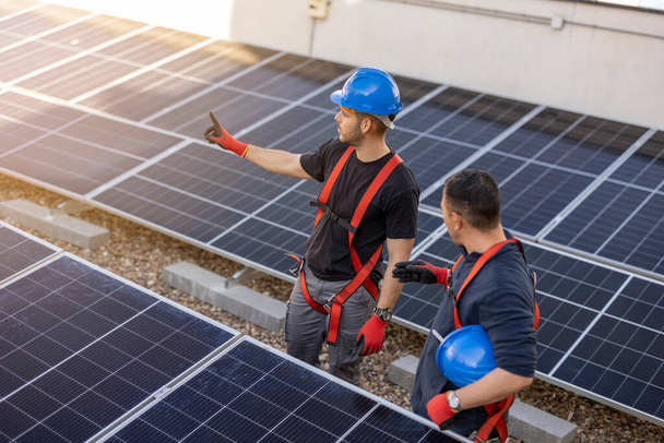 εργάτες που εγκαθιστούν ηλιακούς συλλέκτες, για αποδοτική ενέργεια στην πόλη - Φωτογραφία, εικόνα