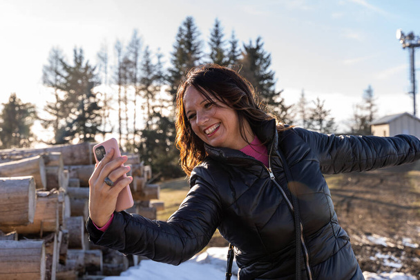 middle aged woman wearing winter clothes taking a selfie over a mountain - concept of people in vacation - Foto, immagini