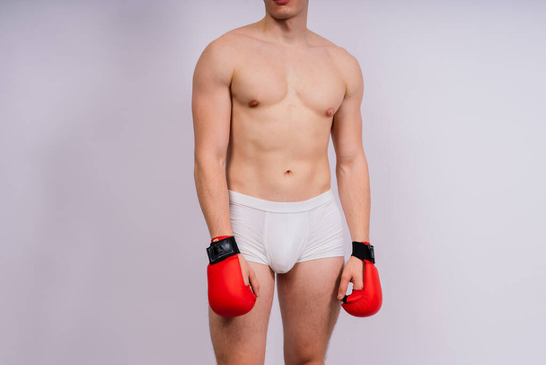 Kehonrakentajat nyrkkeilyhanskat valkoisella taustalla ja valkoiset housut urheilija malli - Valokuva, kuva
