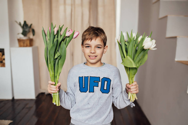 The boy smiles fervently with a bouquet of flowers . - Foto, Imagen