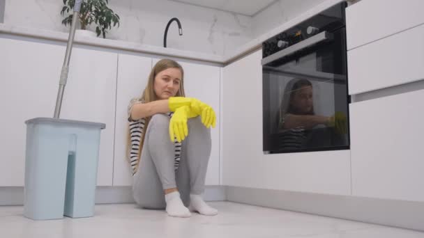 Nuori neiti lepää siivottuaan keittiön. Kotiäiti siivoaa asuntonsa tehdessään kotitöitä. 4k-video - Materiaali, video