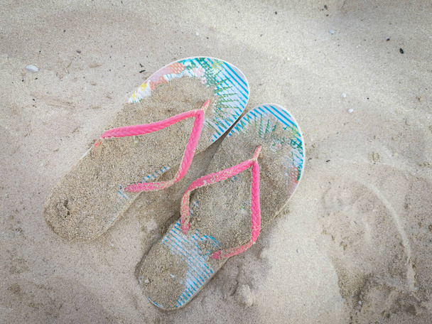 Pare of summer foot slippers on a sandy beach. Relax and holidays. - Foto, Imagem