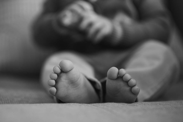 Feet of a small child close up with a blurry photon in black and white - Fotografie, Obrázek