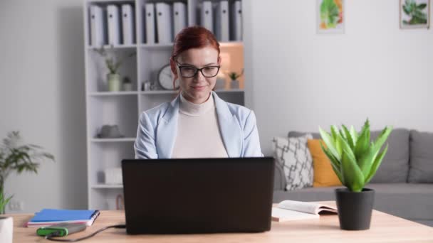 απομακρυσμένη εργασία, πορτρέτο της νεαρής γυναίκας εργάζεται σε έναν υπολογιστή και ελέγχει την αλληλογραφία, ενώ κάθεται στο τραπέζι στο σπίτι - Πλάνα, βίντεο