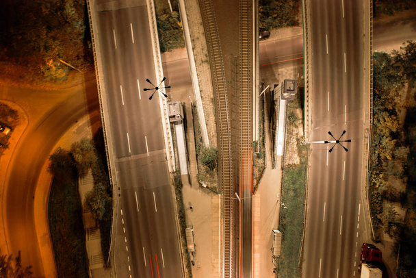 Top down view to road. Romantic night aerial photo of cars traveling. The light on the road at night in city. Background scenic road drone view. Tram railways background - Fotografie, Obrázek