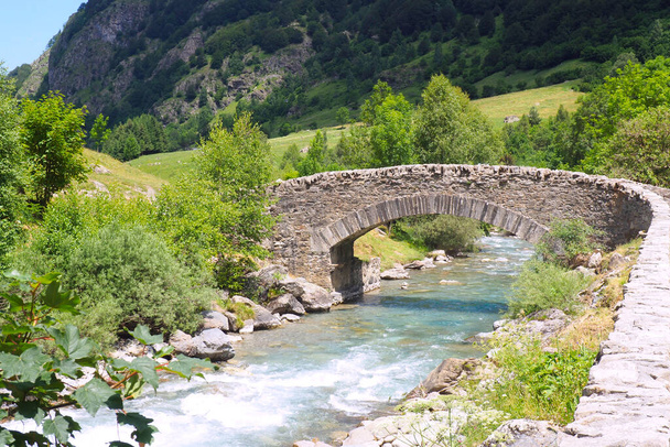 mały stary kamienny most położony u podnóża cyrku Gavarny w Hautes-Pirenejach w pobliżu granicy z Hiszpanią - Zdjęcie, obraz