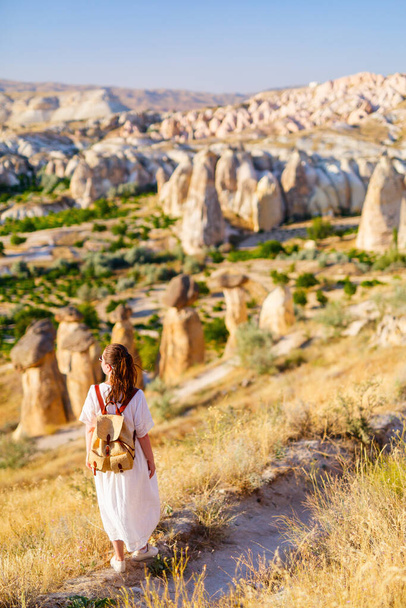 Young woman enjoying stunning sunset while hiking around beautiful valley near Cavusin village in Cappadocia Turkey with amazing rock formations and fairy chimneys - Фото, изображение