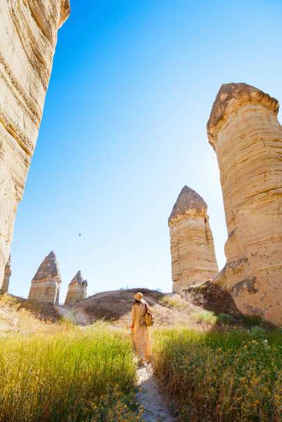 Young woman walking in Gorkundere valley in Cappadocia Turkey among rock formations and fairy chimneys - Φωτογραφία, εικόνα