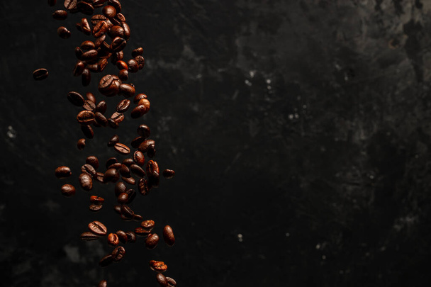 Roasted coffee beans falling on black background, Concept for coffee product advertising, Selective focus, place for text. - Fotografie, Obrázek