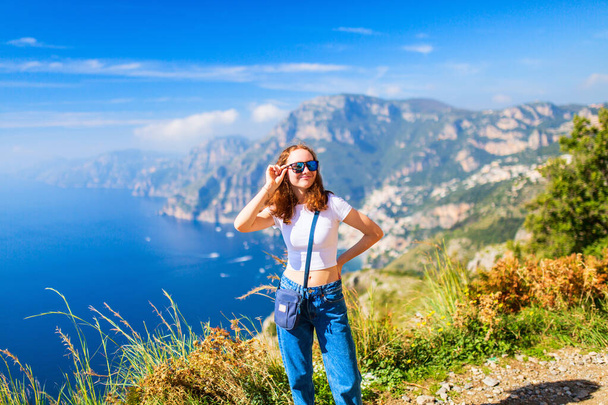 Teenage girl enjoying stunning view over Amalfi coast in Italy while hiking picturesque Path of the Gods trail - 写真・画像