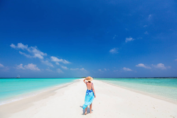 Young woman on white sand tropical beach surrounded by turquoise ocean water of Maldives - Fotografie, Obrázek