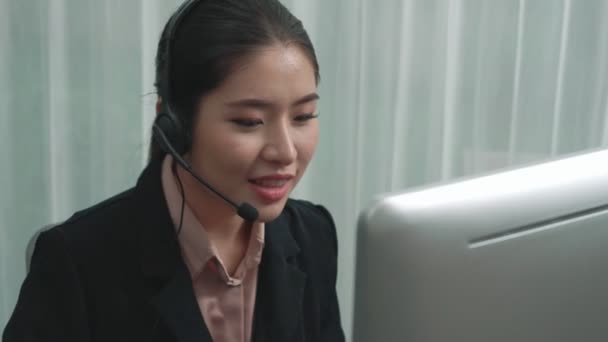 Opérateur de soutien à la clientèle asiatique portant casque et microphone travaillant à son bureau avec ordinateur portable. Employée enthousiaste fournir un service à la clientèle, agent de centre d'appels de soutien aidant les clients. - Séquence, vidéo
