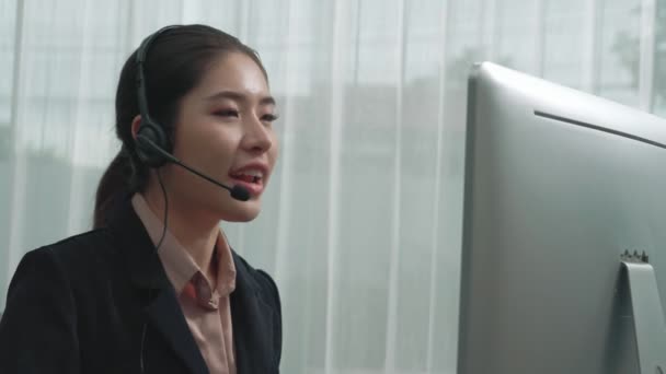 Aziatische klantenservice operator dragen van headset en microfoon werken aan haar bureau met laptop. Enthousiaste vrouwelijke werknemer bieden klantenservice, ondersteunende call center agent helpen klanten. - Video