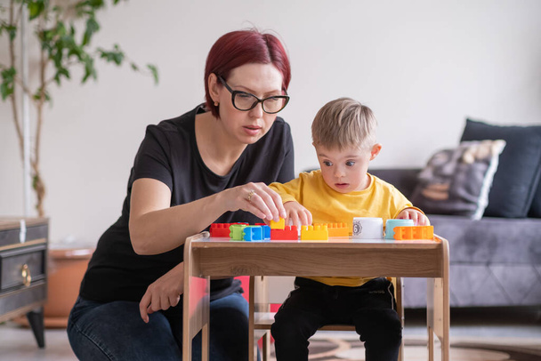child living with Down syndrome learning and playing with educational toys, supported by his mother to reach their full potential - Photo, Image