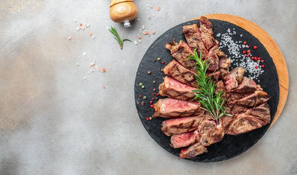 T-bone or porterhouse grilled beef steak with spices and herbs. Long banner format. top view. - Foto, afbeelding