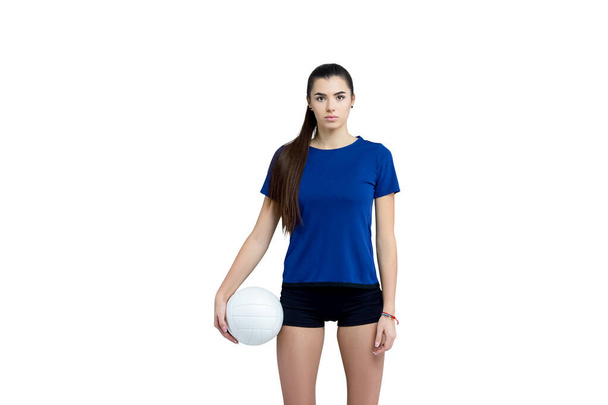 Chica voleibol sostener y patear la pelota en traje azul sobre fondo blanco. Jugador haciendo ejercicio deportivo en casa. Concepto de deporte y recreación - Foto, Imagen