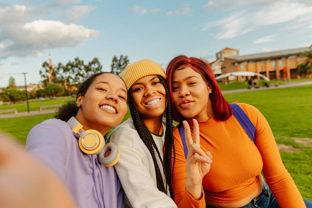 multirassische Gruppe von drei Teenager-Freundinnen, die ein Smartphone benutzen, um gemeinsam Fotos zu machen. Klassenkameraden und Freundschaft. Jugendkultur und Technologie - Foto, Bild