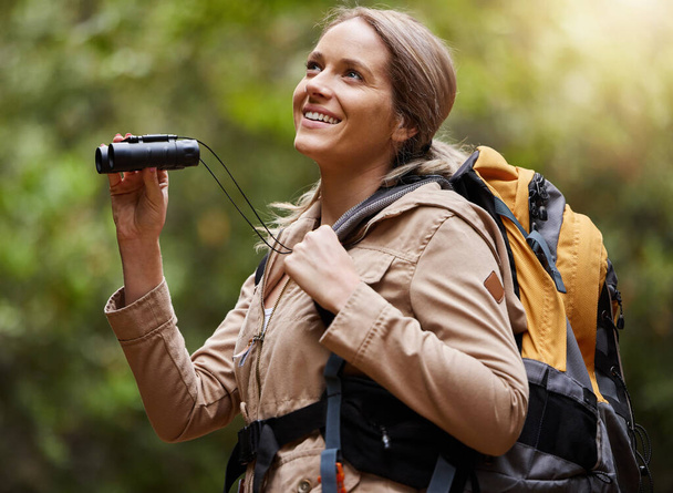 Nature, hiking and woman with binoculars, adventure trail on holiday in African game reserve. Trekking, trees and forest hike, sightseeing and person with smile on happy mountain walk in South Africa. - Photo, Image