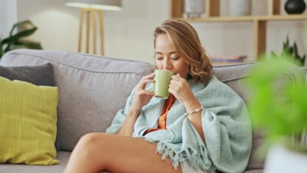 Happy asian woman drinking coffee on living room sofa for peace, calm mindset and easy lifestyle at home. Young female, relaxing and contemplating with tea, latte and hot cocoa on couch for self care. - Footage, Video