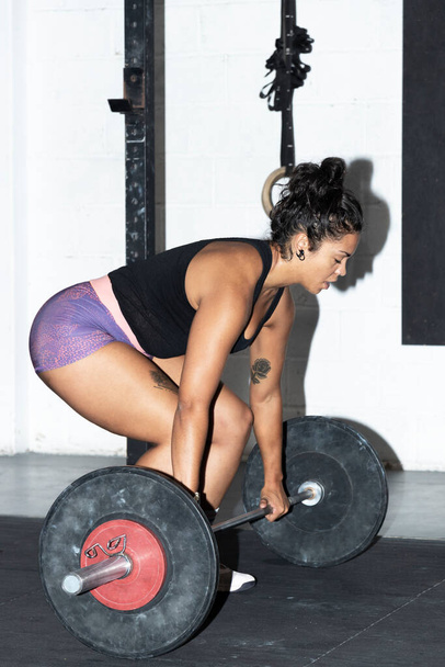 vrouw tillen gewichten in een sportschool - Foto, afbeelding
