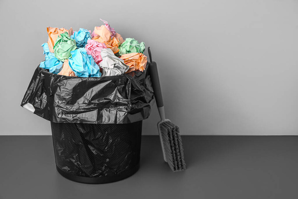 Rubbish bin with crumpled paper and brush near grey wall - Foto, Bild