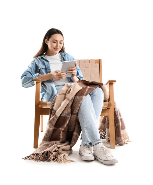 Mladá žena s kostkovaným pomocí tabletu počítače v dřevěném křesle na bílém pozadí - Fotografie, Obrázek